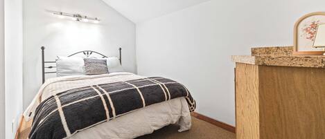 Ein Schlafzimmer mit einem Bett, einem Holzkopfende, einem Nachttisch und einer Wandleuchte.
