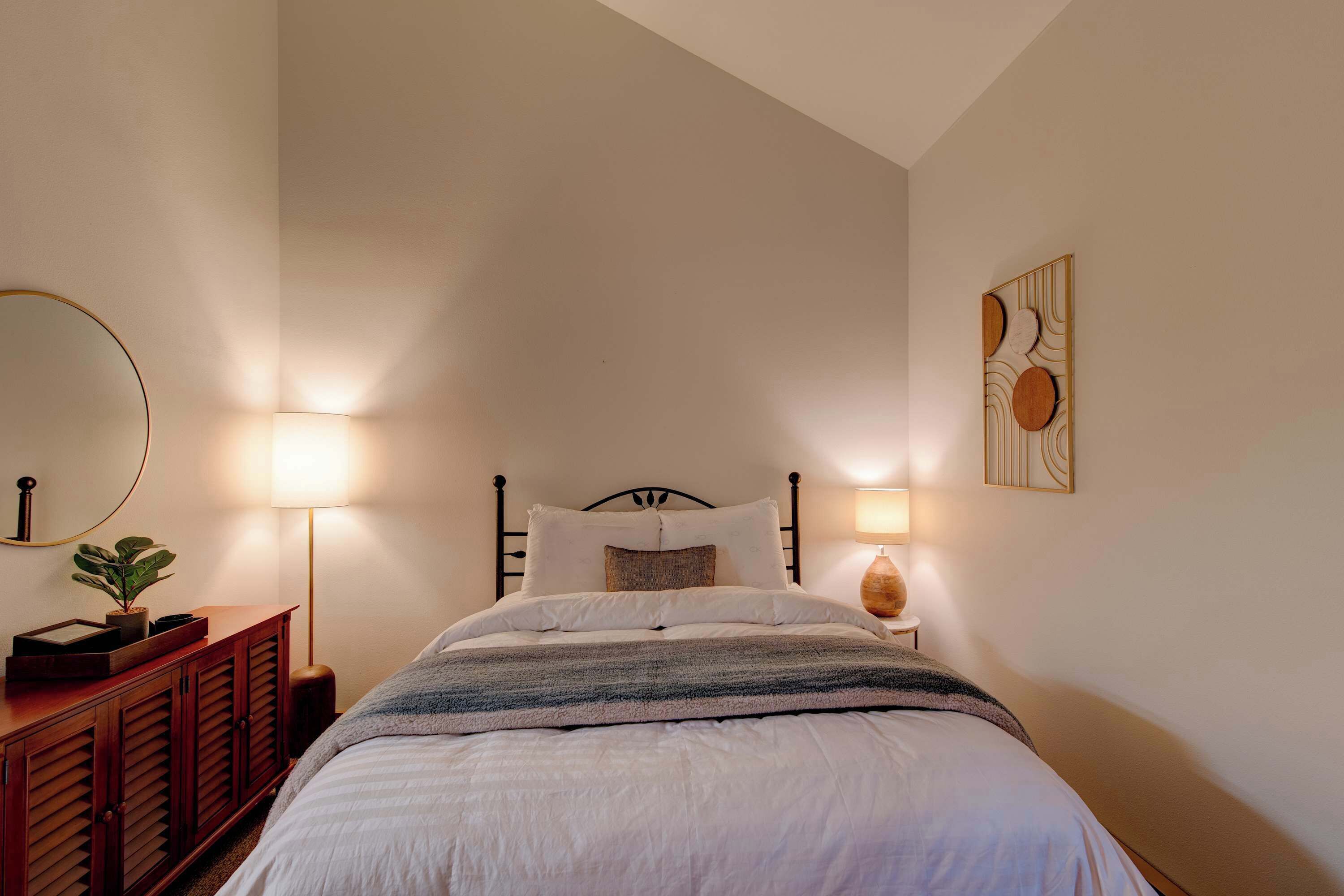 A neatly made bed with white bedding, a wooden headboard, and a bedside table with a lamp.