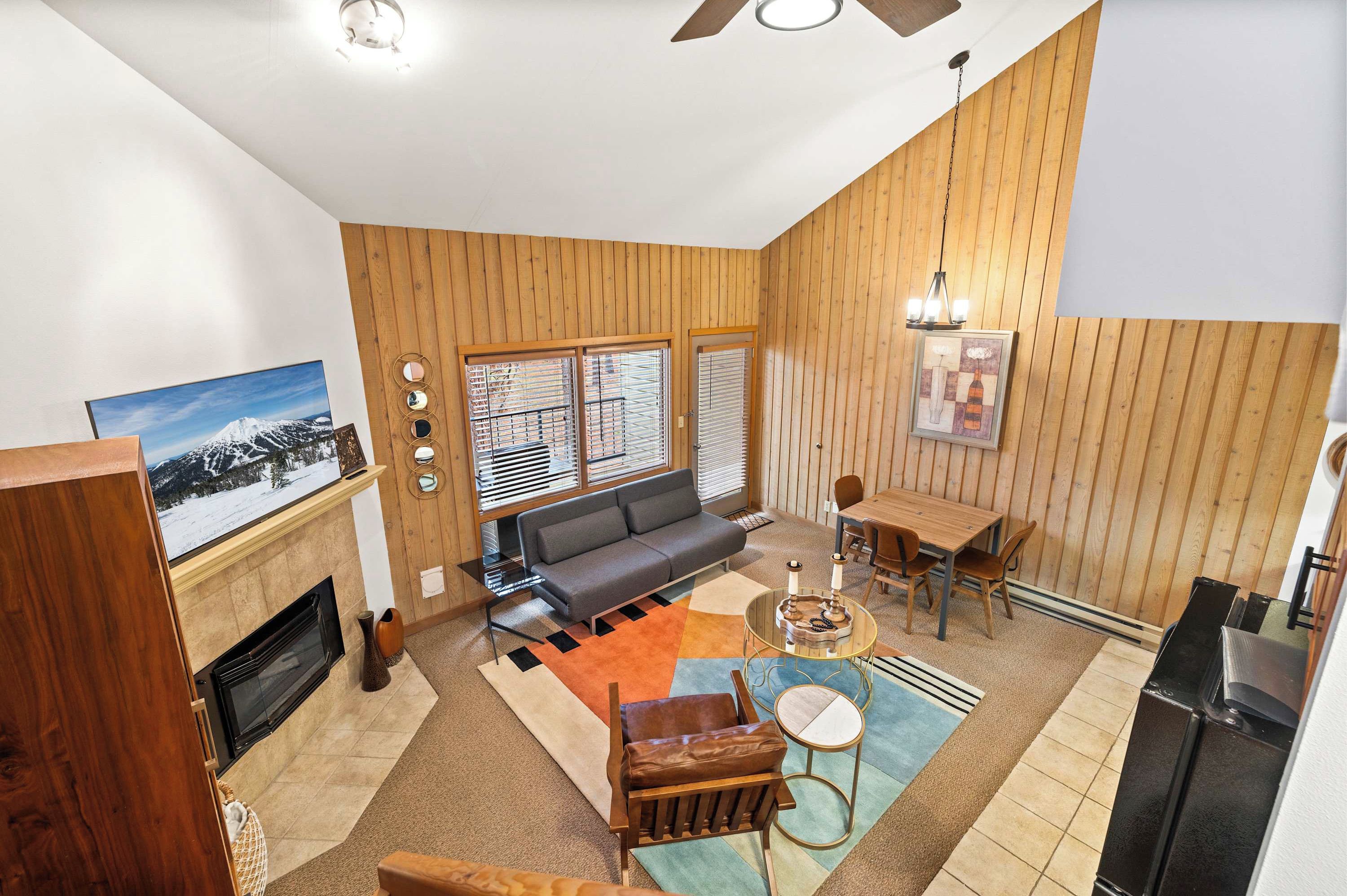 A modern living room with a fireplace, a sofa, a dining table, and a kitchen area.