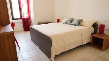 A bedroom with a bed, bedside tables, a desk, and a chair.