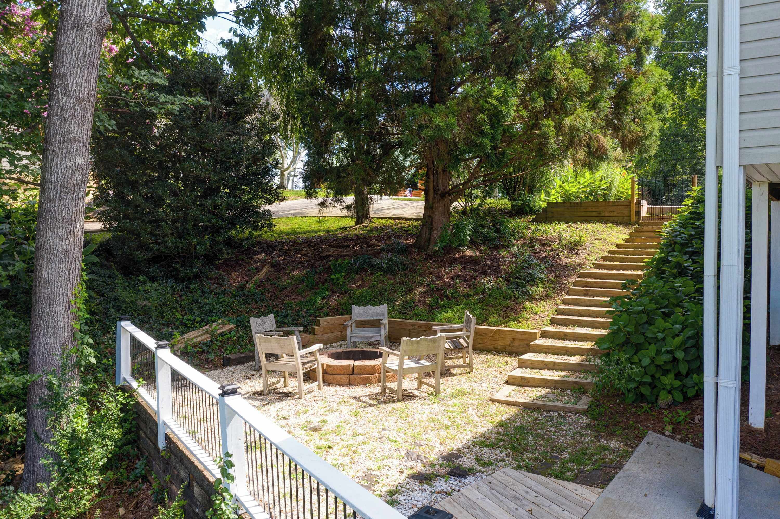 A deck with outdoor seating, a fire pit, and a staircase leading to a house.