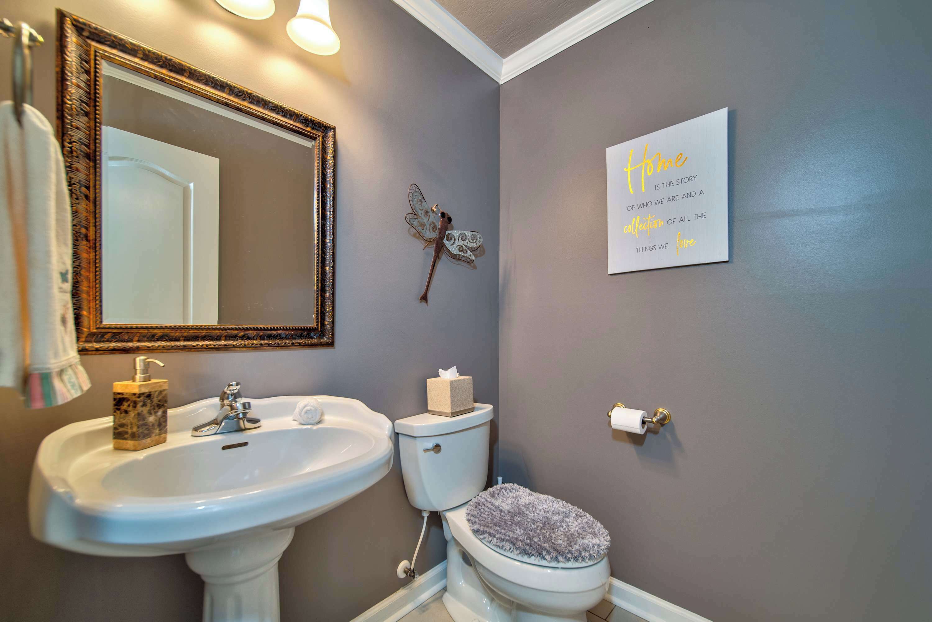 A bathroom with a white sink, a toilet, a decorative butterfly, and a motivational quote on the wall.