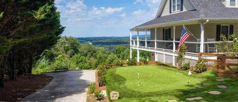 A house with a porch, a lawn, and a view of the landscape.