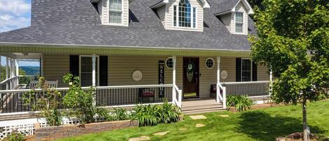 A two-story house with a front porch, a covered patio, and a well-maintained lawn.
