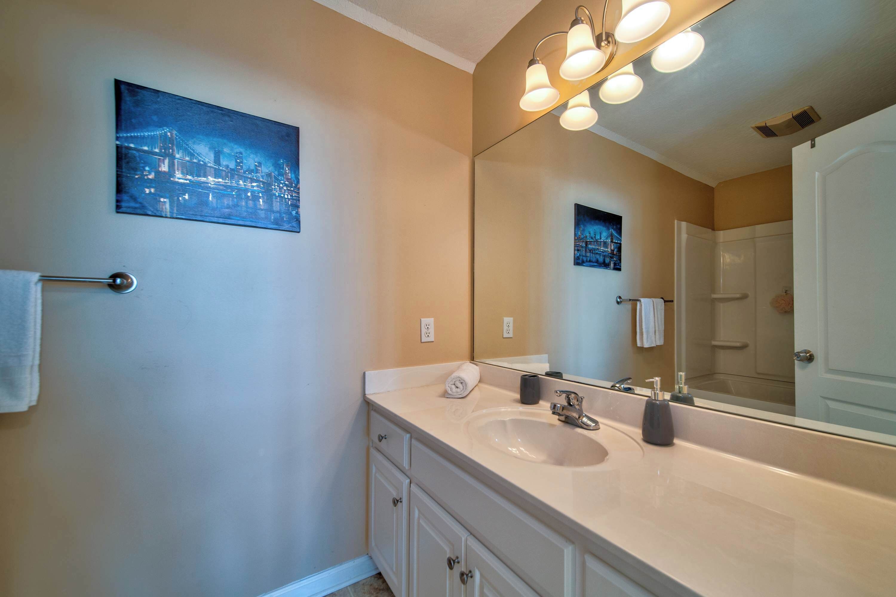 A bathroom with a large mirror, a sink, and a towel rack.