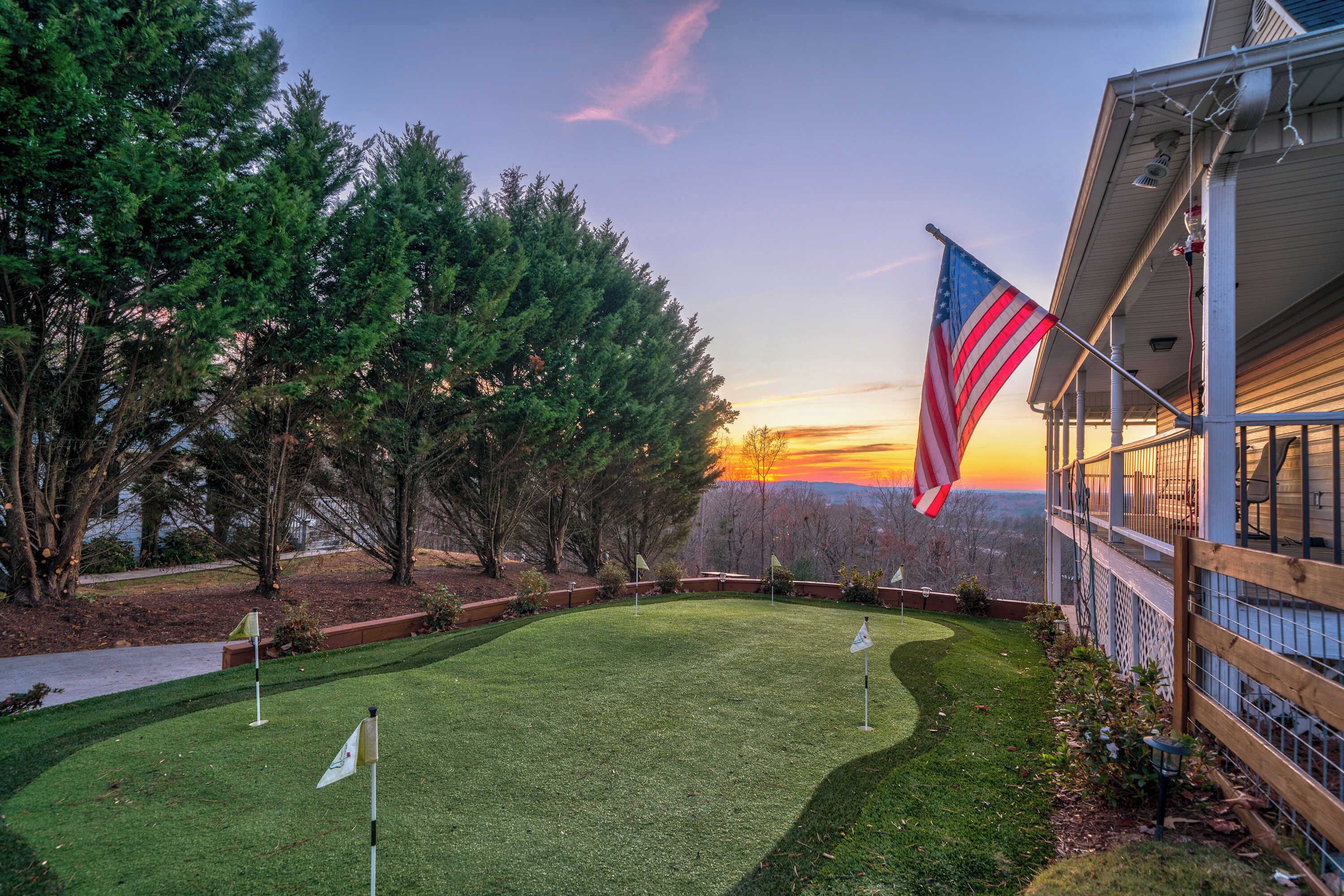 A well-maintained lawn with a flagpole and flags, a wooden fence, and a building with a balcony.