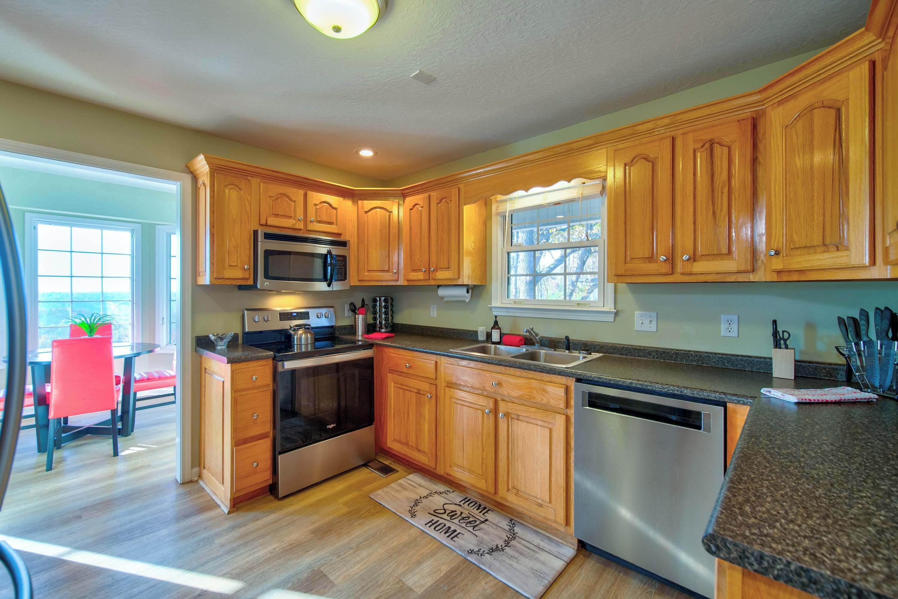 A kitchen with wooden cabinets, stainless steel appliances, a window, and a red chair.
