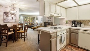 Uma cozinha moderna com armários brancos, uma ilha central e um espaço de refeições com cadeiras de madeira e um sofá.