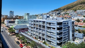 Un hotel de varios pisos con balcones, estacionamiento y vista a la ciudad.