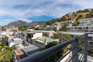 A residential area with modern apartment buildings, a construction crane, and a mountain in the background.
