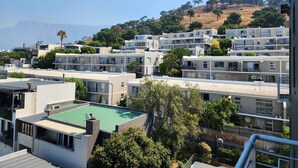 Zona residencial amb edificis moderns, una piscina i un turó ple d'arbres.