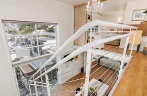 A multi-level interior with a staircase, a chandelier, and a view of the cityscape through large windows.