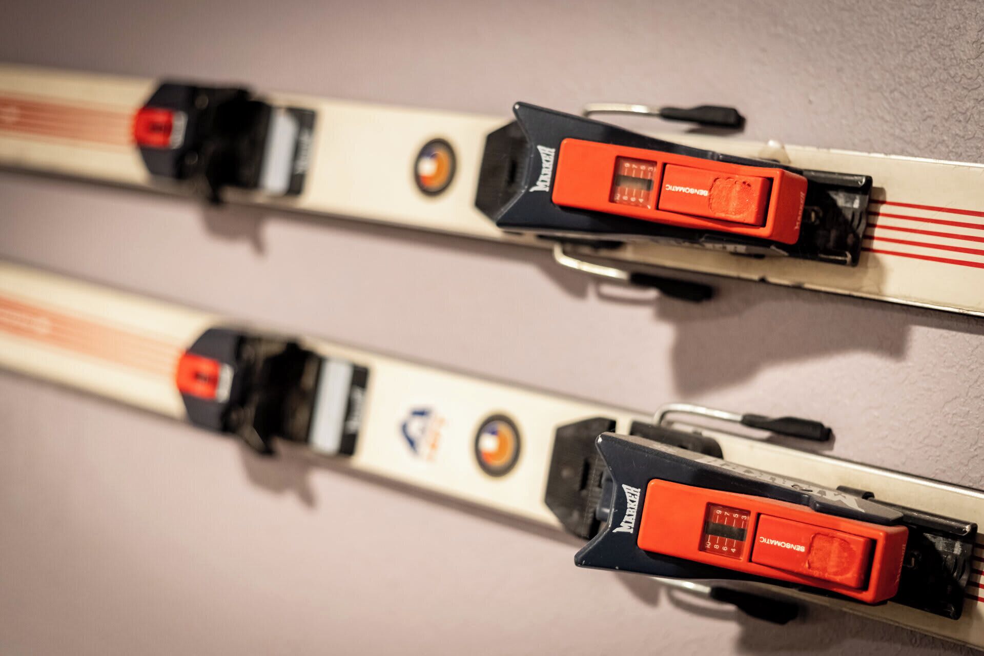 A close-up of two ski poles with red and black grips, and a visible brand name on the grip.
