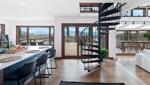Une cuisine moderne dotée d’un îlot central, de grandes fenêtres et d’un escalier en colimaçon.