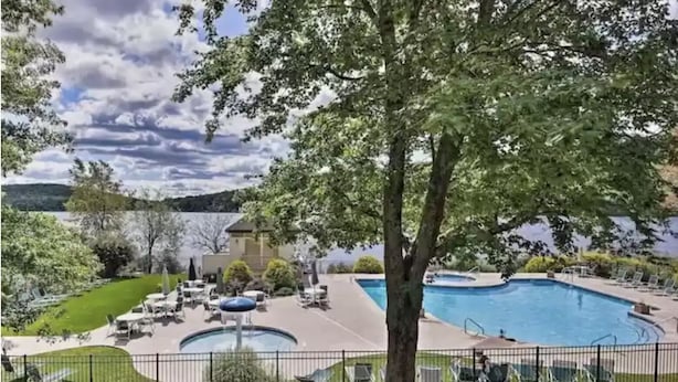 Zona de piscina con sillas de descanso y un edificio al fondo.