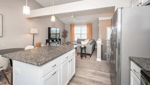 A modern kitchen with granite countertops, white cabinetry, and a stainless steel refrigerator. - Ark Adventure Retreat (Walton)