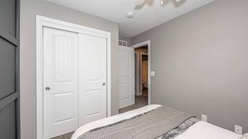 A bedroom with a bed, two white doors, and a ceiling fan.