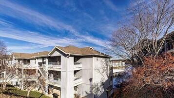 A multi-story residential building with a central staircase, balconies, and a view of a river.