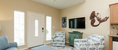 A living room with a ceiling fan, a television, and patterned furniture.