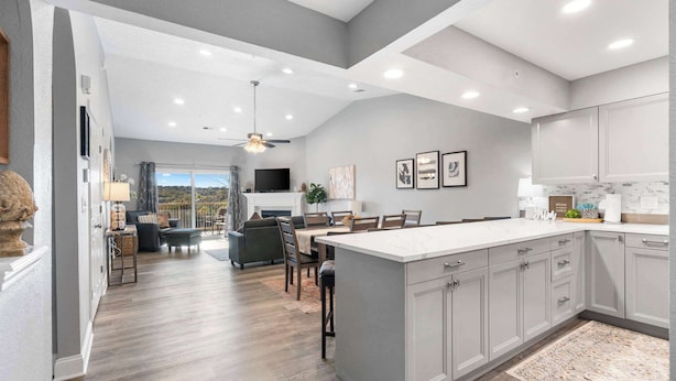 A modern kitchen with grey cabinets, a large island, and a dining area with a view. - Great Escape II - Resort Style 2 BDR Condo on Golf Course w/ Pool! (Branson)