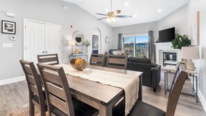 A modern living room with a dining area, a fireplace, and a large window with a view. - Great Escape II - Resort Style 2 BDR Condo on Golf Course w/ Pool! (Branson)