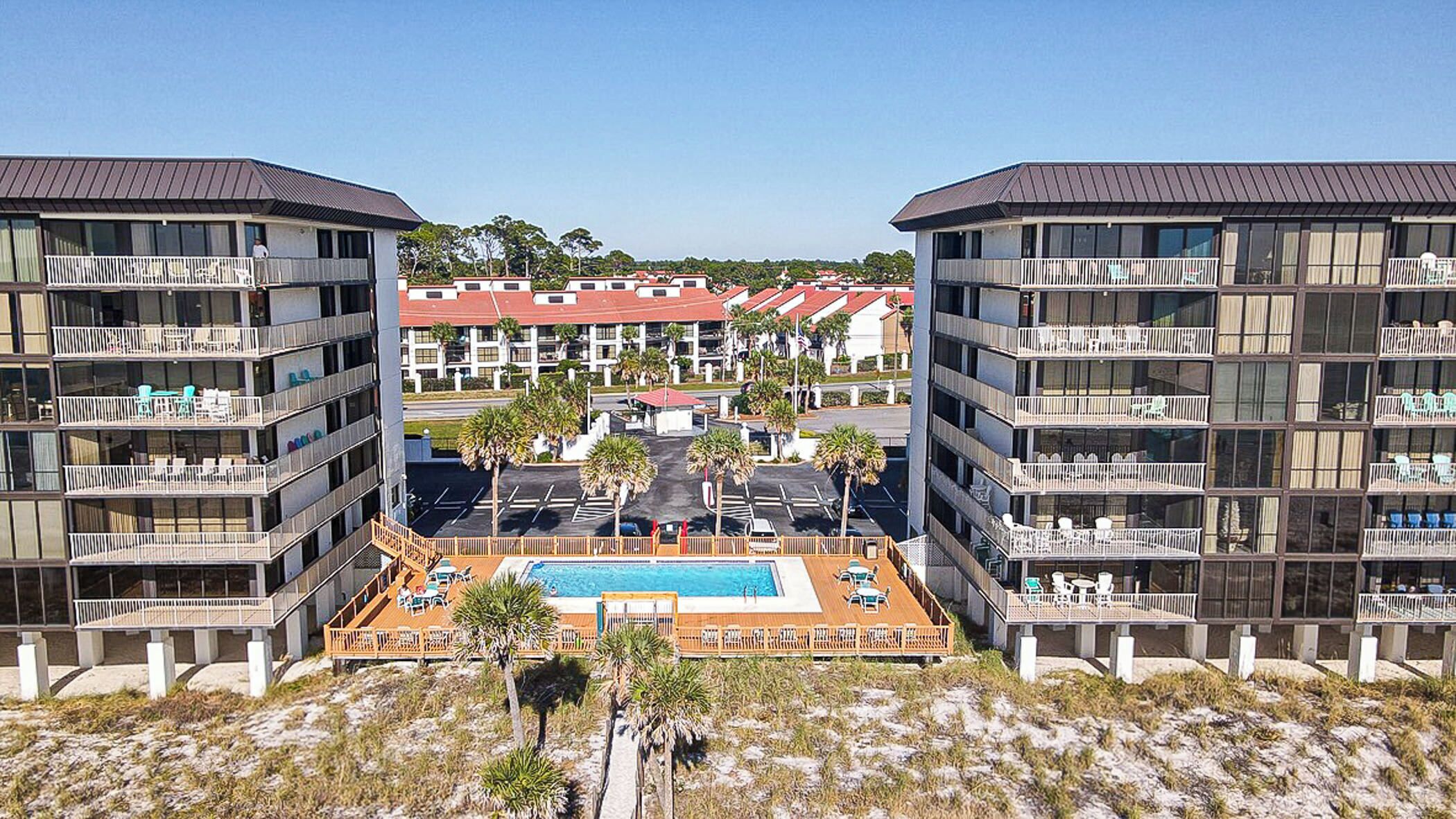 A modern hotel with multiple floors, a central swimming pool, and a view of other buildings in the background.