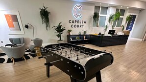 Ein Kicker-Tisch in einer modernen Lobby mit einer Rezeption und einer Lounge-Ecke.