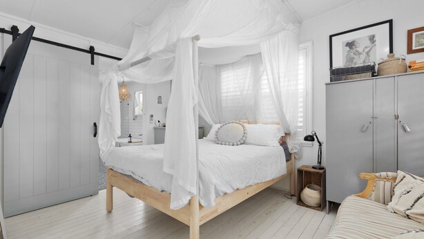 Une chambre à coucher avec un lit à baldaquin, une table de chevet, une lampe, une armoire et un canapé à rayures.