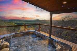 A hot tub on a wooden deck with a scenic view of mountains and trees. - 50 Mi Mtn Views! New Build! 2 Kings + Bunks! HotTub•Slide•Dinos•PuttPutt (Broken Bow)