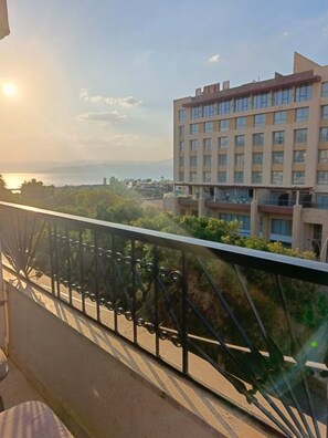 A balcony with a metal railing overlooking a cityscape with buildings and a body of water in the distance. - Eden hotel aqaba (Aqaba)