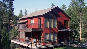 Una casa a due piani di colore rosso con un balcone al piano superiore, circondata da alberi.