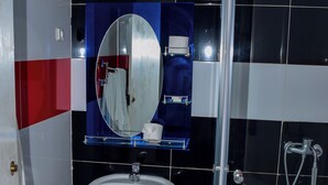 Une salle de bain avec un lavabo blanc, un miroir et une douche.