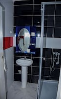 Un baño con lavamanos blanco, espejo y ducha.