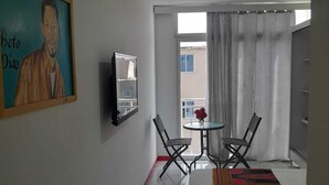 Une chambre d’hôtel avec un lit, un tableau, une petite table avec des chaises et une vue par la fenêtre.