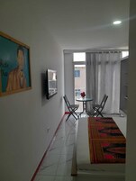 Habitación de hotel con cama, un cuadro, una mesita con sillas y vistas por la ventana.