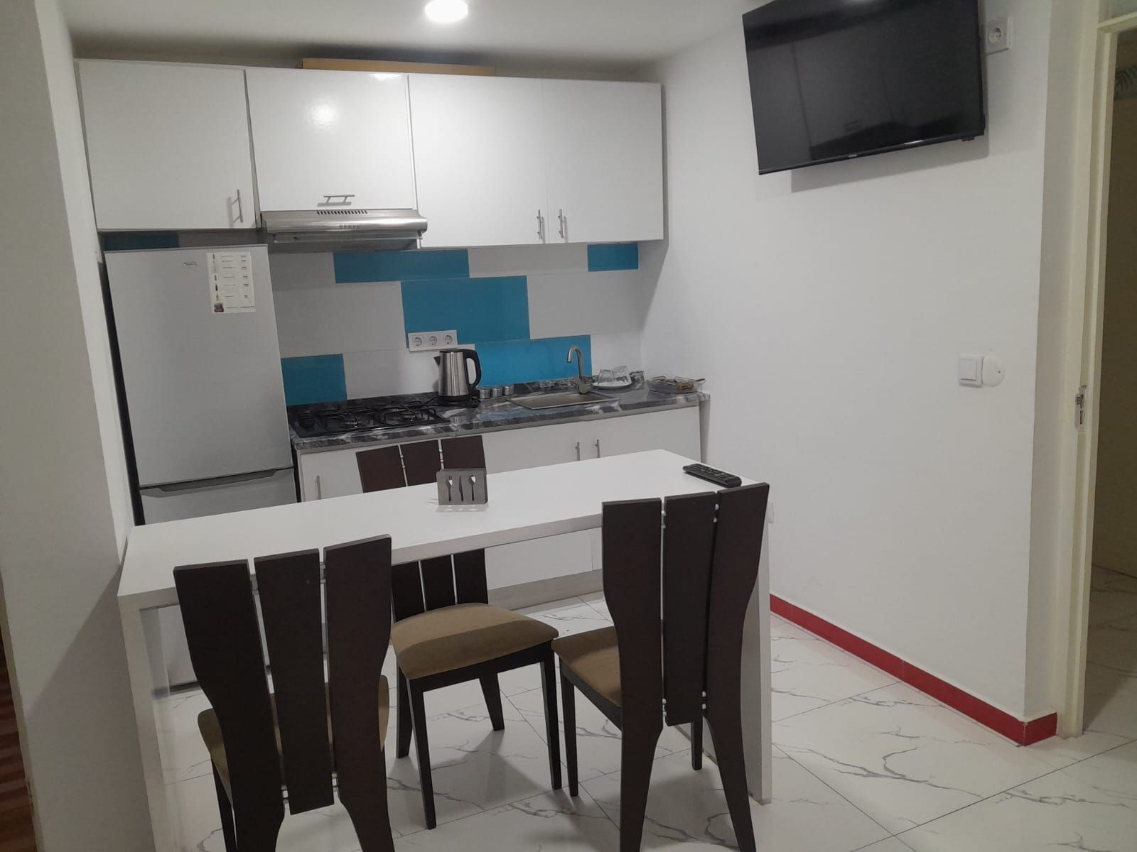 A compact kitchen with white cabinets, a gas stove, and a small dining table with chairs.