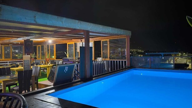 An outdoor pool area with a covered seating area and tables. - Hotel Principal (Tarrafal)