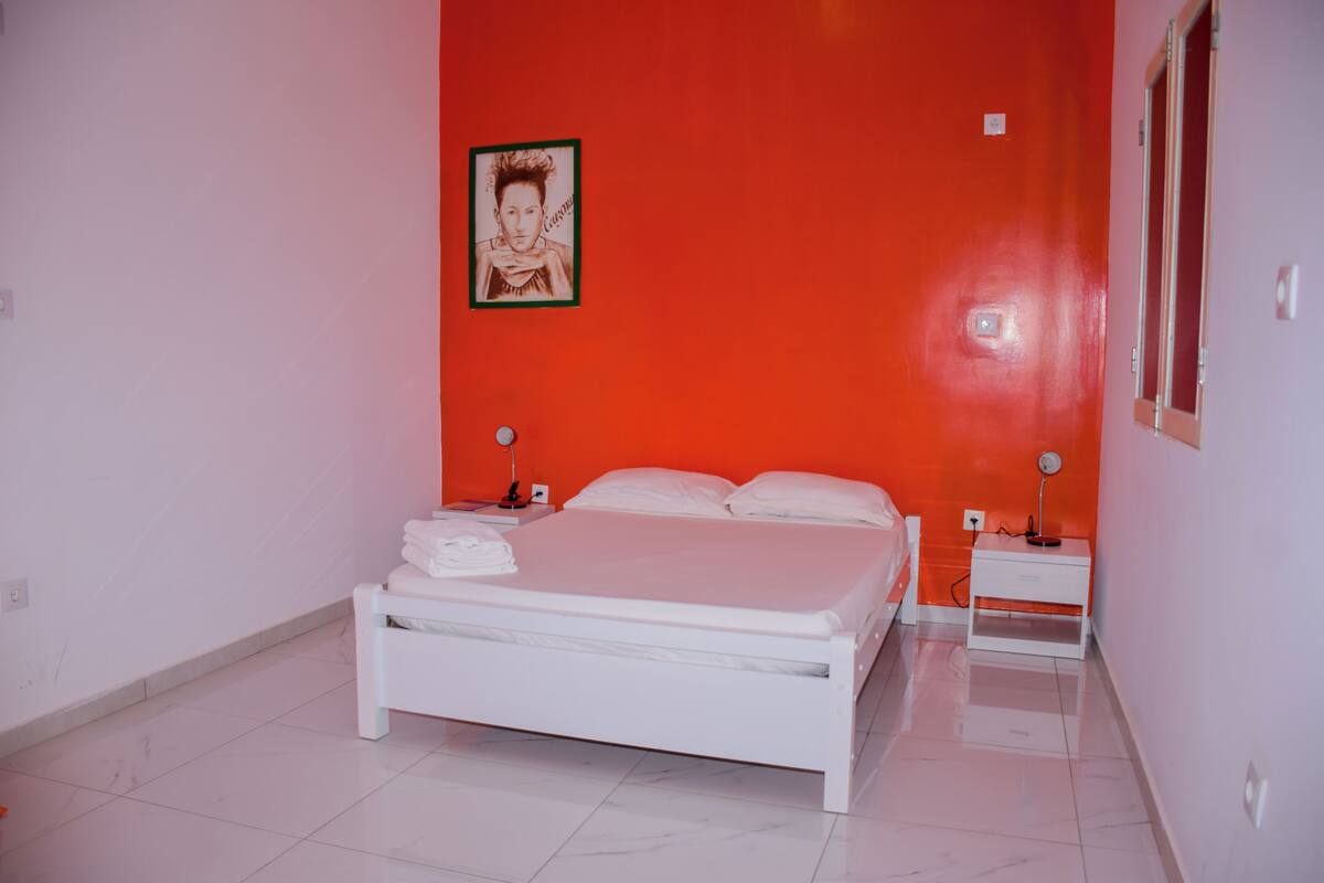 Un dormitorio con una cama blanca, dos mesitas de noche y un cuadro enmarcado en la pared.
