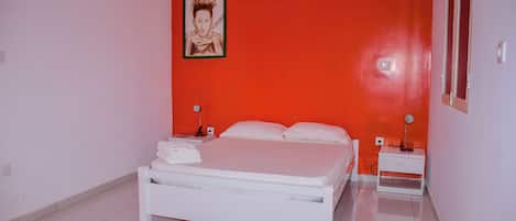 Un dormitorio con una cama blanca, dos mesitas de noche y un cuadro enmarcado en la pared.