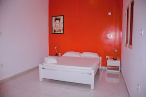 Un dormitorio con una cama blanca, dos mesitas de noche y un cuadro enmarcado en la pared.