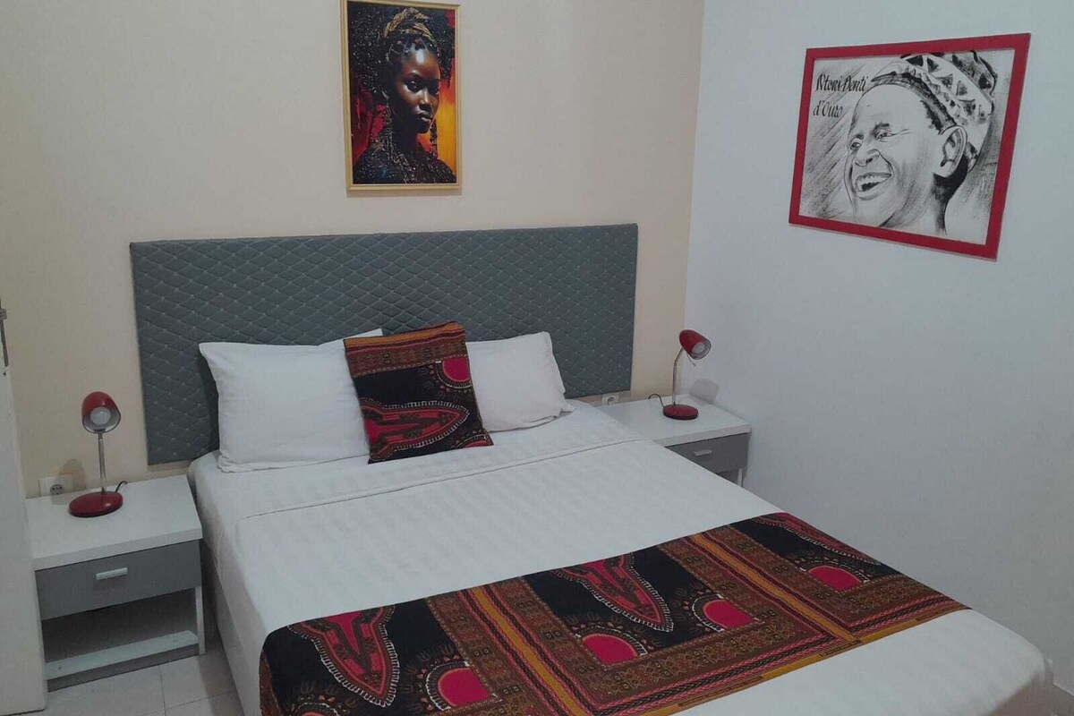 A neatly made bed with a patterned throw, a headboard, and two bedside tables with lamps.