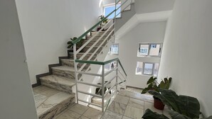A staircase with marble steps and a glass railing, leading to an upper floor with windows. - Hotel Principal (Tarrafal)