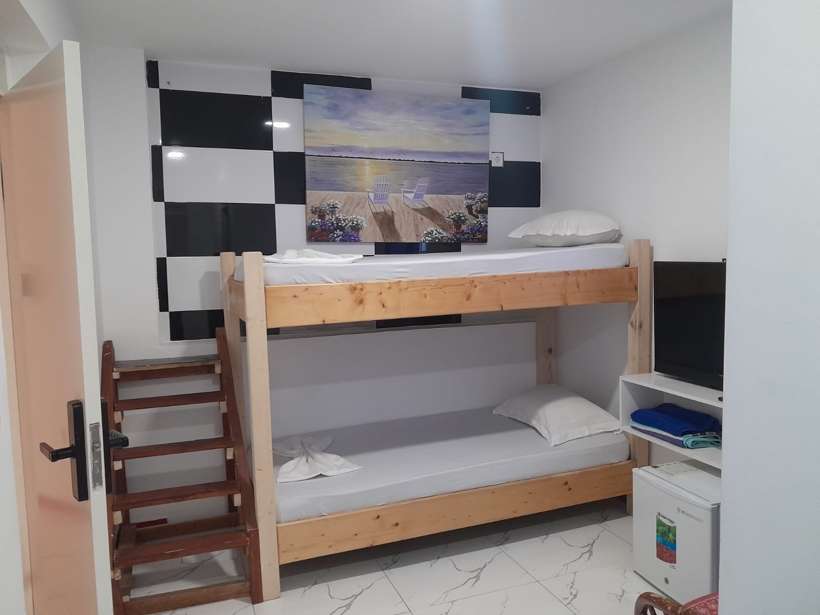 Ein Stockbett mit einer Leiter, einem Fernseher und einem kleinen Schrank.