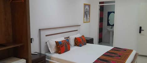 A bedroom with a bed, bedside tables, a wardrobe, and a mirror.