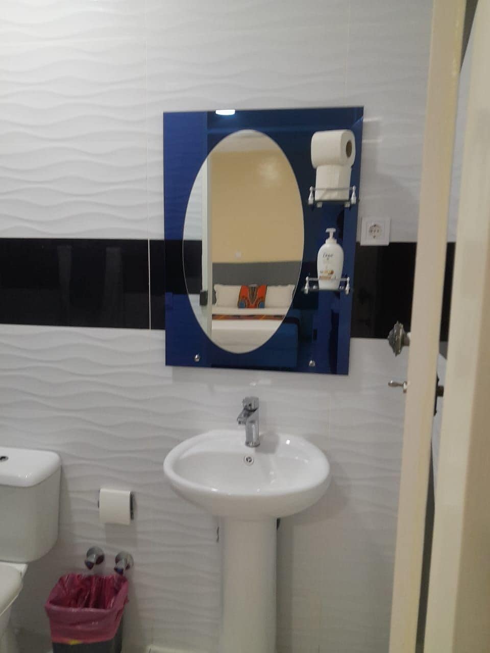 A bathroom with a white sink, a mirror, and a toilet.