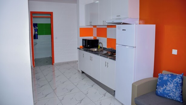 Une cuisine moderne avec des meubles blancs, un plan de travail noir et un pare-feu rouge et blanc.