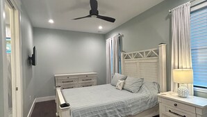 Un dormitorio con cama, mesita de noche y ventilador de techo.