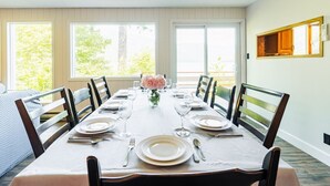 Comedor con una mesa dispuesta para seis comensales, ventanas amplias y vistas al verdor exterior.