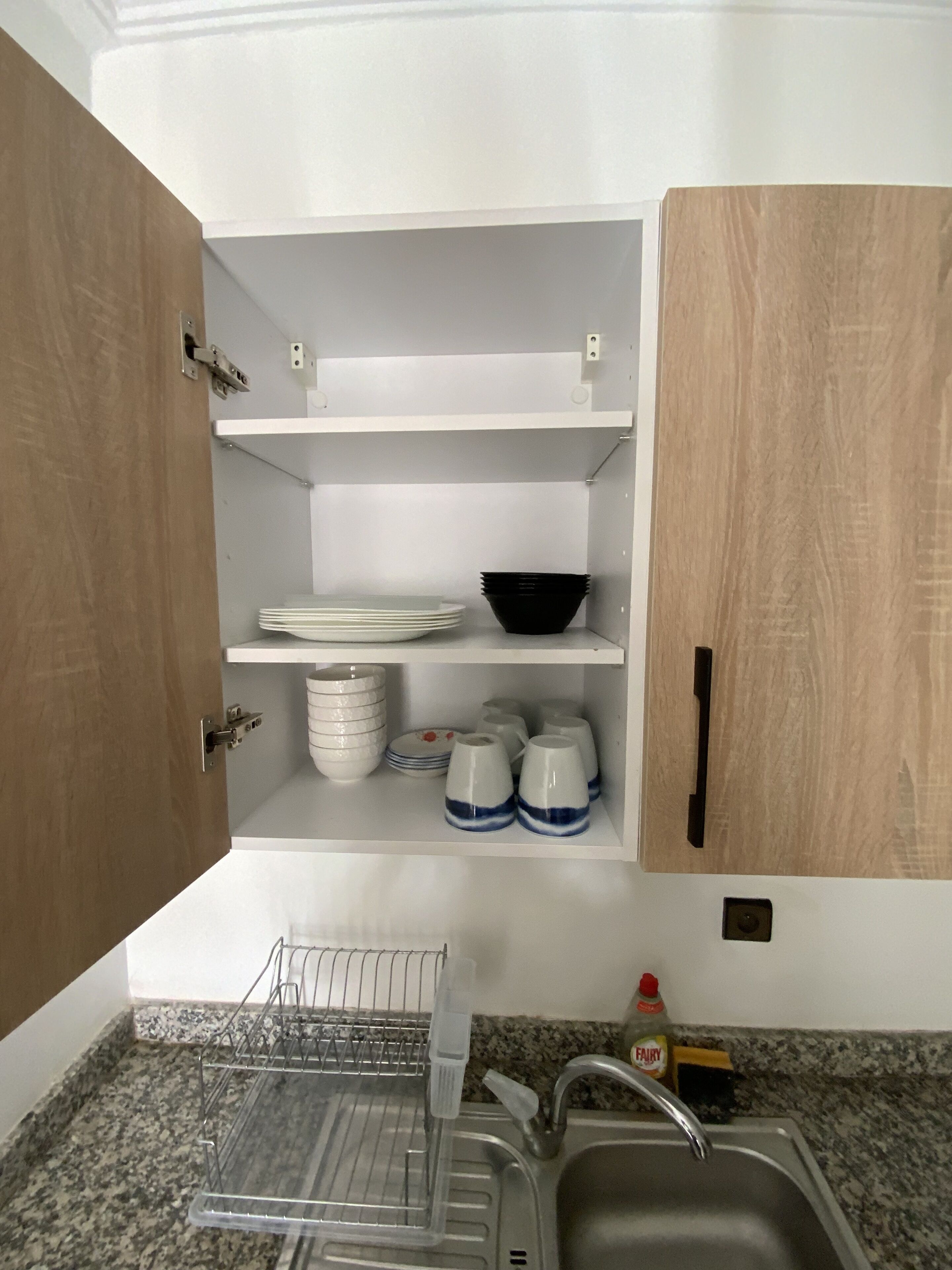 A kitchen with a granite countertop, a stainless steel sink, and wooden cabinets.