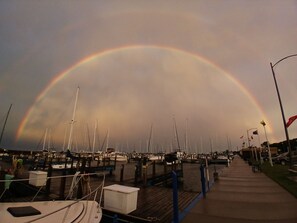A marina with boats docked and a rainbow in the sky.